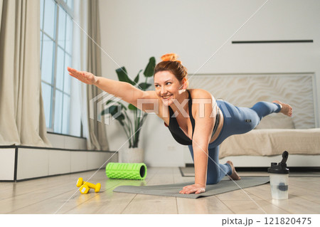 Yoga fitness workout training. Woman practicing yoga at home. Plus size female doing sports exercise on yoga mat indoor. Girl in sportswear have training workout for weight loss. Sport and fitness 121820475