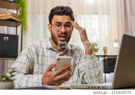 Indian young businessman using smartphone receive bad news fortune loss game fails at home office 121820775