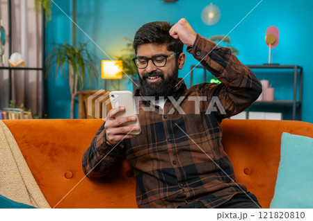Surprised excited Indian man use smartphone reading good news amazed by online bet bid game win 121820810