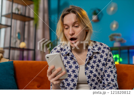 Surprised excited young woman winner holding smartphone reading good news amazed by online game win Surprised excited young woman winner holding smartphone reading good news amazed by online game win 121820812