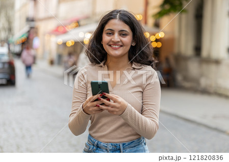 Indian woman use smartphone typing text messages browsing internet finishing work looking at camera 121820836