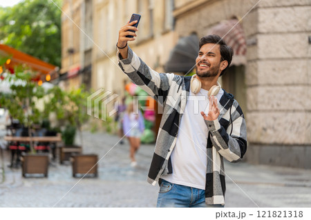 Cheerful Arabian man blogger taking selfie on smartphone, talking video call standing in city street Cheerful Arabian man blogger taking selfie on smartphone, talking video call standing in city street 121821318