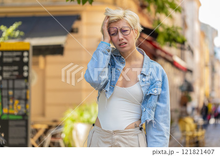 Sad unhappy young woman thinks over life concerns, suffers from unfair situation on city street 121821407