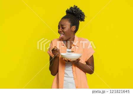 African American woman tasting soup disappointed expression too salty spicy hot holding spoon bowl 121821645