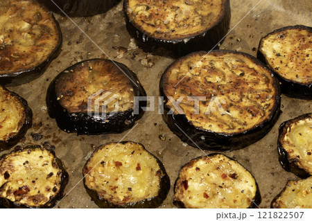 A roasted sliced seasoned aubergine eggplant courgette with salt and herbs cooked in the oven close up 121822507