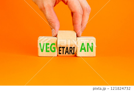 Vegetarian or vegan symbol. Concept words Vegetarian Vegan on wooden block. Beautiful orange table orange background. Vegan hand. Healthy lifestyle vegetarian or vegan concept. Copy space. 121824732