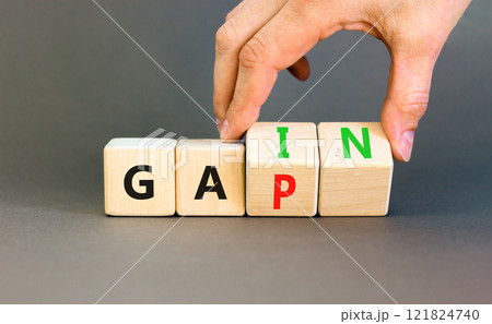 Gain or gap symbol. Concept words Gain Gap on wooden block. Beautiful grey table grey background. Businessman hand. Business gain or gap concept. Copy space. Gain or gap symbol. Concept words Gain Gap on wooden block. Beautiful grey table grey background. Businessman hand. Business gain or gap concept. Copy space. 121824740