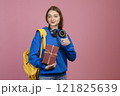 Front view of teenage girl standing, holding present, gift box. Beautiful schoolgirl looking at camera, smiling, showing super. Concept of school, college, university and youth. 121825639