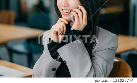 スマホで話す笑顔の女性・ビジネスウーマン スマホで話す笑顔の女性・ビジネスウーマン 121825774