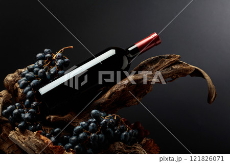 Bottle of red wine with blue grapes on old wooden snags. Bottle of red wine with blue grapes on old wooden snags. 121826071