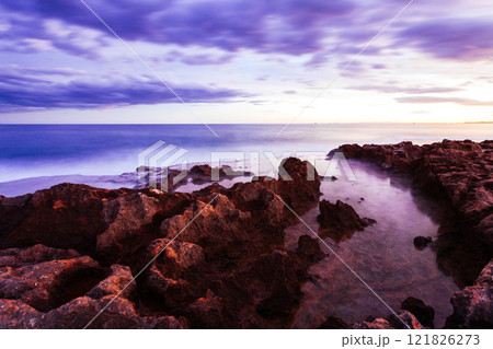 Stunning purple sunset over rocky coastline. Concept of natural beauty, tranquility, and the timeless connection between land and sea. Stunning purple sunset over rocky coastline. Concept of natural beauty, tranquility, and the timeless connection between land and sea. 121826273