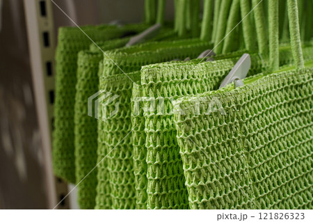 Vibrant green shopping bags hanging in a store display for eco-friendly shoppers Vibrant green shopping bags hanging in a store display for eco-friendly shoppers 121826323