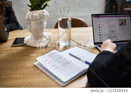 Workspace with Decorative Bust Planter, Open Notebook, Laptop, Water Pitcher, Creative Office Setting Concept 121826410