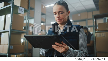 Female Logistics Specialist Uses Tablet Computer, Checks Inventory 121826741