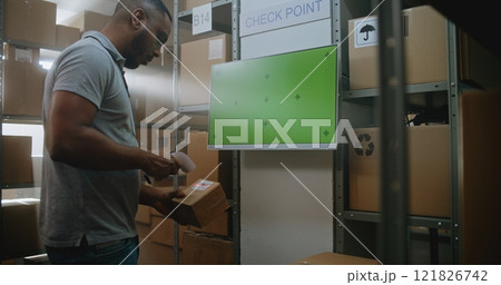 African American Warehouse Associate Checks Parcel Information at Terminal 121826742