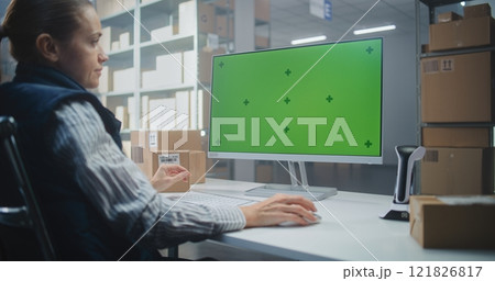 Female Logistics Specialist Works on Computer in Warehouse Facility. PC Screen Shows Chroma Key Female Logistics Specialist Works on Computer in Warehouse Facility. PC Screen Shows Chroma Key 121826817