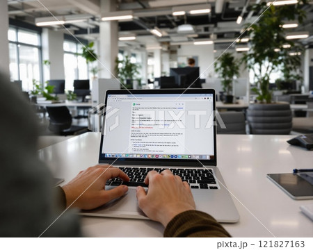 A Contemporary Workspace Showcasing a Laptop with Hands Actively Typing on the Keyboard 121827163