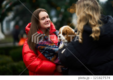Friends enjoying a chilly afternoon with a dog in a park decorated for the holidays 121827574