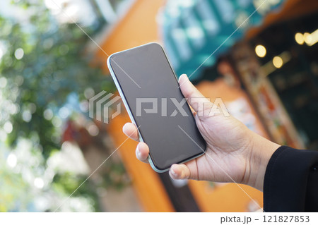 A Person Holding a Smartphone While Outdoors in a Very Vibrant Setting A Person Holding a Smartphone While Outdoors in a Very Vibrant Setting 121827853