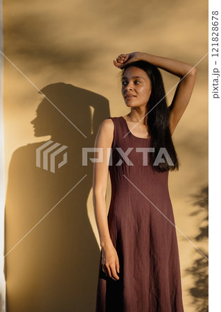 young African American woman in brown dress poses in park. happy female model at sunset in summer 121828678