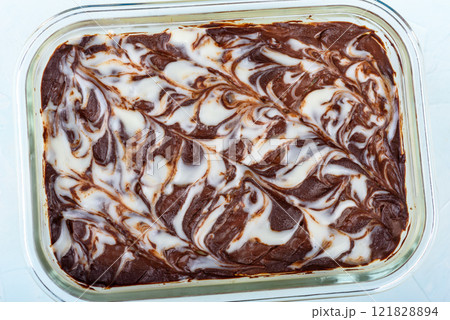 Top view of layered dessert with chocolate and cream swirl in glass form placed on light background. 121828894