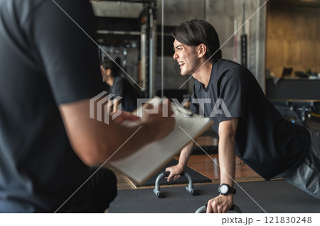 スポーツジムでパーソナルトレーニングを受ける若いアジア人男性 121830248