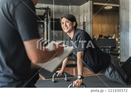 スポーツジムでパーソナルトレーニングを受ける若いアジア人男性 スポーツジムでパーソナルトレーニングを受ける若いアジア人男性 121830372