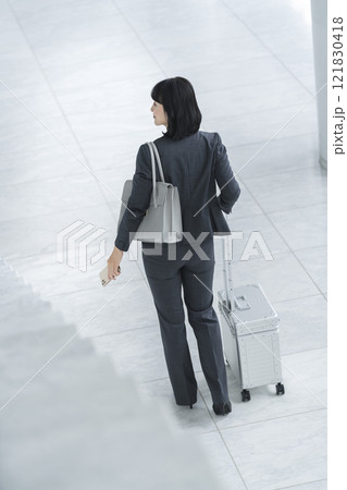 キャリーバッグを引いて歩くミドルのビジネスウーマン　後ろ姿 121830418
