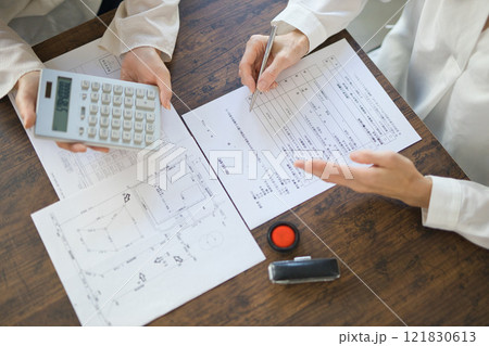 不動産の契約を結ぶ女性2人の手元 121830613