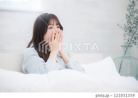 朝の寝起きのベッドで欠伸をする若い女性 121831359