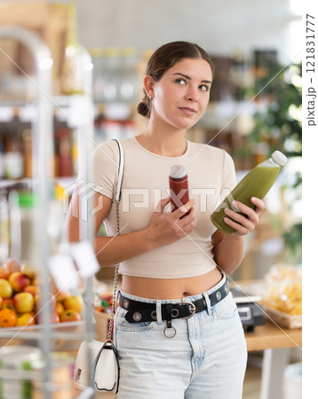Young woman chooses red and green smoothie Young woman chooses red and green smoothie 121831777