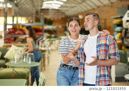 Spouses look for something in furniture store, searching for perfect item to complete patio Spouses look for something in furniture store, searching for perfect item to complete patio 121831950