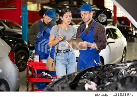 Male worker of auto service speaking to female client concerning his notes on paper 121831973