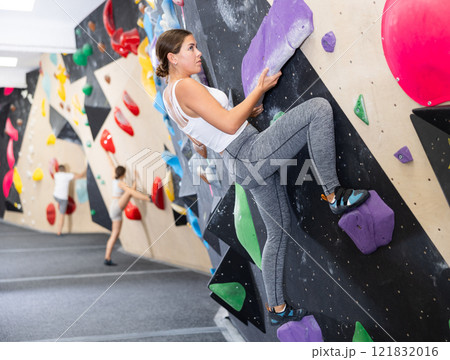 Motivated girl climbing without ropes on artificial bouldering wall Motivated girl climbing without ropes on artificial bouldering wall 121832016