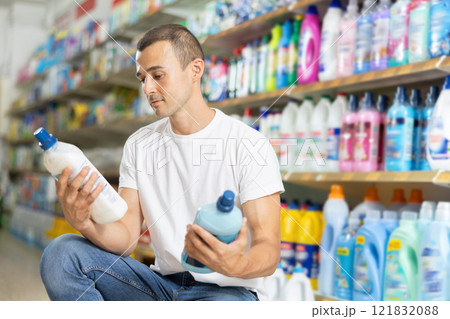 Man carefully selects cleaning product in industrial section of supermarket Man carefully selects cleaning product in industrial section of supermarket 121832088