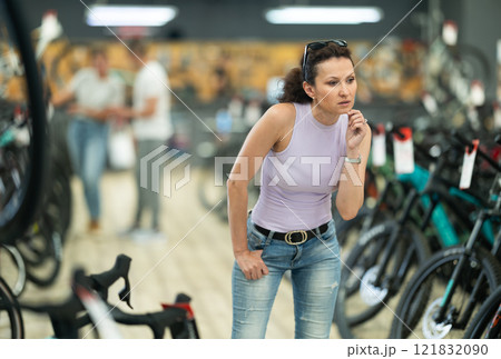 Avid female cyclist exploring variety of bicycles in store Avid female cyclist exploring variety of bicycles in store 121832090