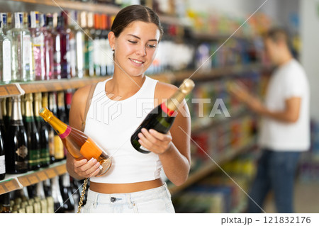 Woman chooses bottle of champagne in shop store 121832176