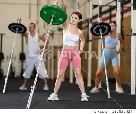 Young woman training with barbell in gym 121833424