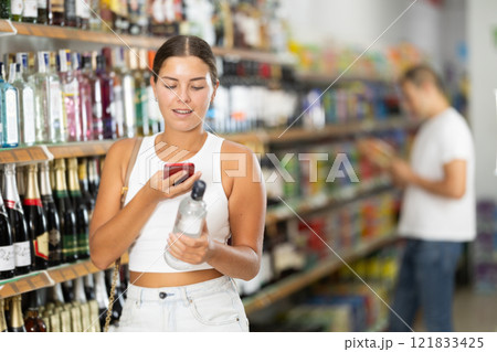 Young woman scanning qr code for vodka Young woman scanning qr code for vodka 121833425