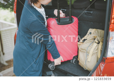 車のトランクにスーツケースを積む女性 121833659