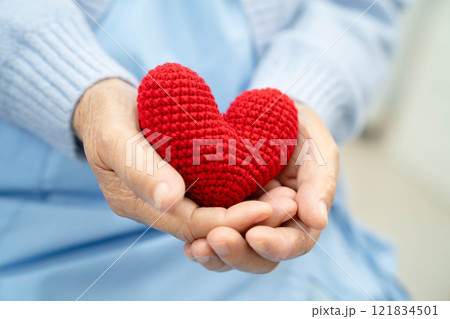 Asian elder senior woman patient holding red heart in hospital. Asian elder senior woman patient holding red heart in hospital. 121834501