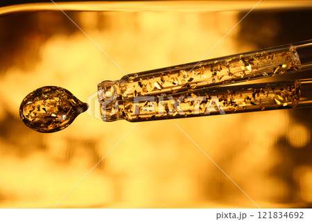 24 k gold facial serum in a pipette on a gold background. 24 k gold facial serum in a pipette on a gold background. 121834692