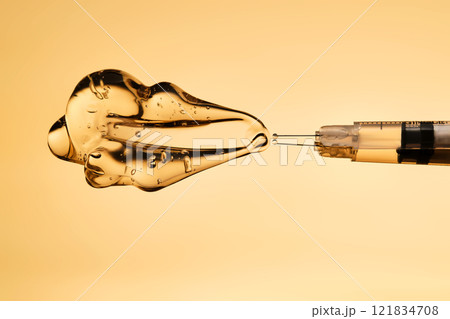 A drop of gel pours from a syringe for cosmetic procedures. A drop of gel pours from a syringe for cosmetic procedures. 121834708