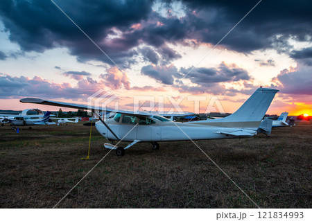 Small private airplanes parked at the airfield at scenic sunset 121834993