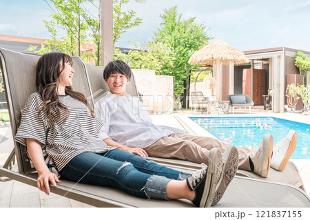 旅行でリゾートホテルのプールサイドに座るカップル・夫婦 旅行でリゾートホテルのプールサイドに座るカップル・夫婦 121837155