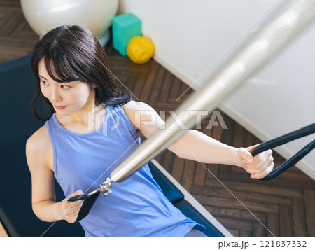マシンピラティスのトレーニングをする女性 マシンピラティスのトレーニングをする女性 121837332