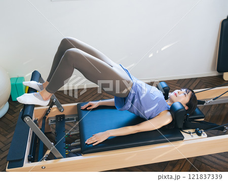 マシンピラティスのトレーニングをする女性 マシンピラティスのトレーニングをする女性 121837339