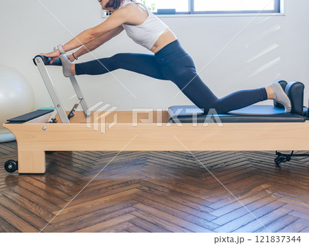 マシンピラティスのトレーニングをする女性 マシンピラティスのトレーニングをする女性 121837344