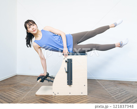 マシンピラティスのトレーニングをする女性 マシンピラティスのトレーニングをする女性 121837348