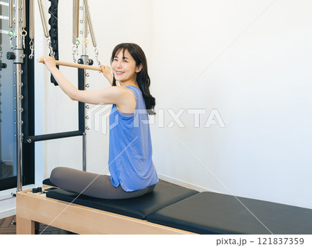 マシンピラティスのトレーニングをする女性 マシンピラティスのトレーニングをする女性 121837359